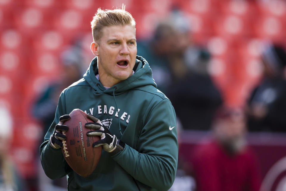 Josh McCown holding a football in an Eagles sweatshirt. 