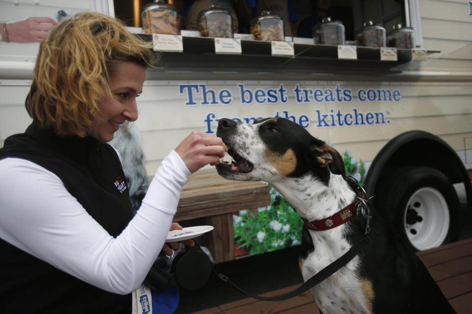 Chrissy Trampedach (L) feeds her four-year-old dog Enzo in front of Milo's Kitchen Treat Truck in San Francisco, California June 27, 2014. Milo's Kitchen, a San Francisco-based pet food company, on Friday started its nationwide food truck tour specifically catered to dogs. REUTERS/Stephen Lam (UNITED STATES - Tags: BUSINESS ANIMALS)