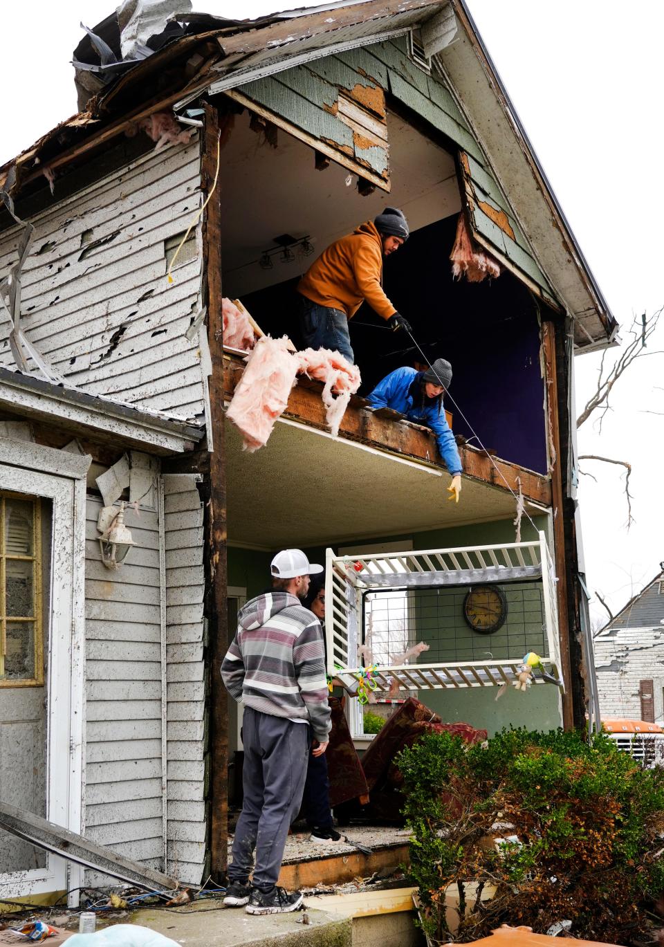 Siblings Michael Golden, top left, and Alyssa Golden lower a crib to the ground Friday, March 15, 2024 at a tornado-damaged home in Lakeview, Ohio. Blaine Schmitt, lower left, lives in the home with his wife, Brittany, and their two children. Only Blaine and a friend were home at the time of the tornado on Thursday night, March 14, 2024.