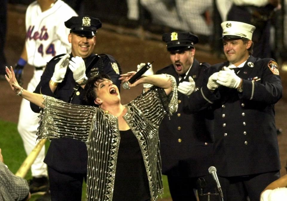 FILE - In this Sept. 21, 2001, file photo, Liza Minnelli belts out "New York, New York" during the seventh inning stretch as New York City policemen and firemen cheer her on during the New York Mets' baseball game against the Atlanta Braves at Shea Stadium In New York. (AP Photo/Bill Kostroun, File)