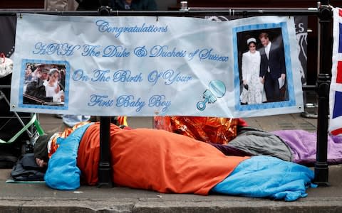 Royal fan lays in a sleeping bag beneath a congratulatory banner near Windsor Castle in Windsor early on Tuesday - Credit: Adrian Dennis/AFP