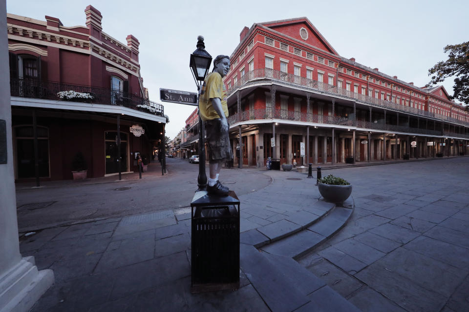 FILE - In this March 20, 2020 file photo, street performer Eddie Webb looks around the nearly deserted French Quarter looking to make money in New Orleans. Where political divides marred early recovery efforts after Hurricane Katrina in 2005, Louisiana is showing rare political unity in the fight against the new coronavirus. (AP Photo/Gerald Herbert, File)