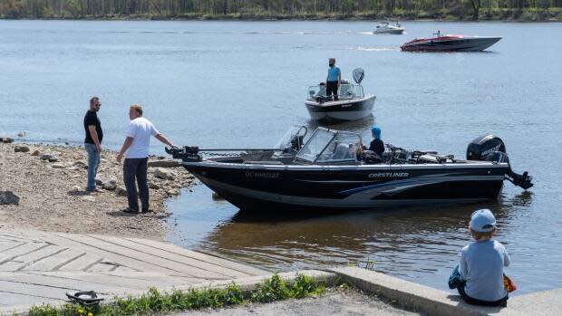 Boaters stand on a boat launch at the Kitchissipi Marina in Gatineau, Que., in May 2021. May was one of the driest on record for the region, and there have already been reports of low water levels on the Ottawa River causing damage to boats. (CBC - image credit)