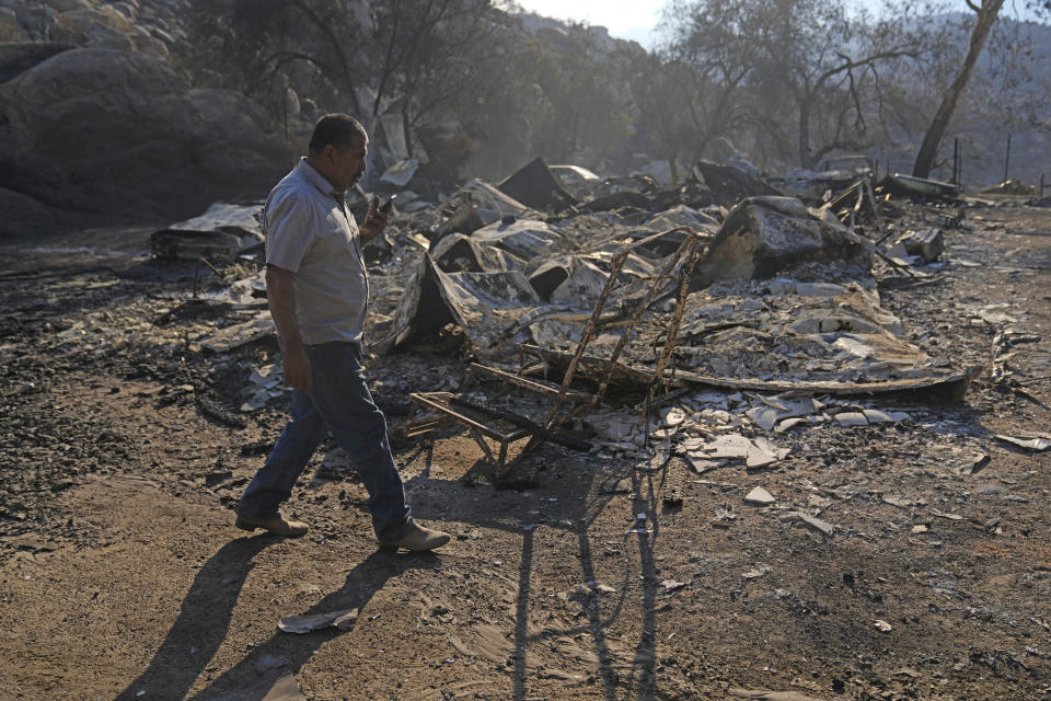 Luis Quinonez talks to a neighbor on the phone while surveying the damage to his property after the Highland Fire passed through Tuesday, Oct. 31, 2023, in Aguanga, Calif. (AP Photo/Marcio Jose Sanchez)