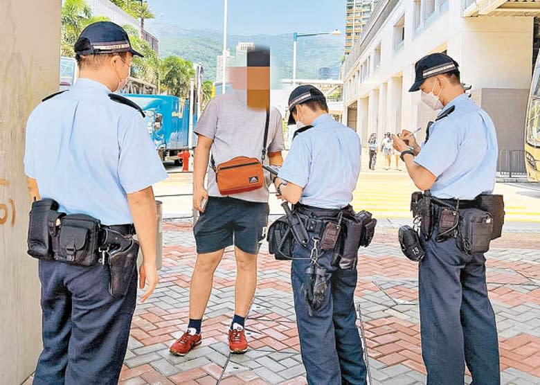 警員向違防疫規例的市民發出告票。