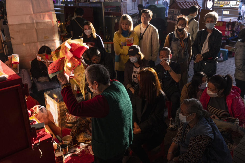 A practitioner performs a "villain hitting" ceremony as customers watch under the Canal Road Flyover in Hong Kong, on Sunday, March 5, 2023. (AP Photo/Louise Delmotte)