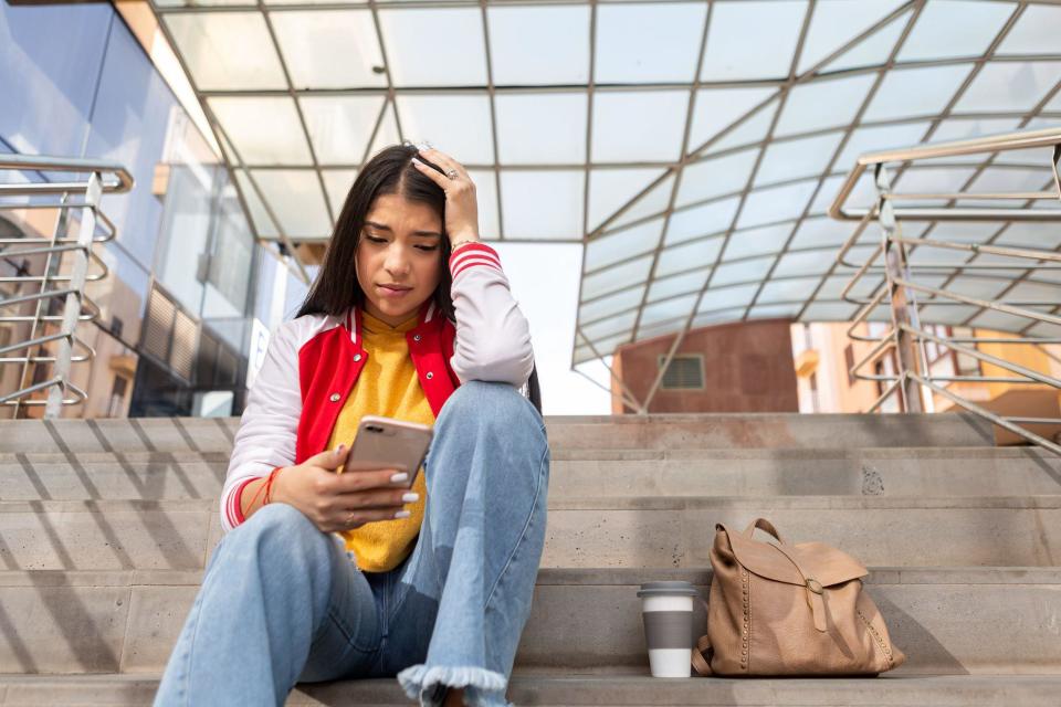 Una joven con su celular en la mano. 