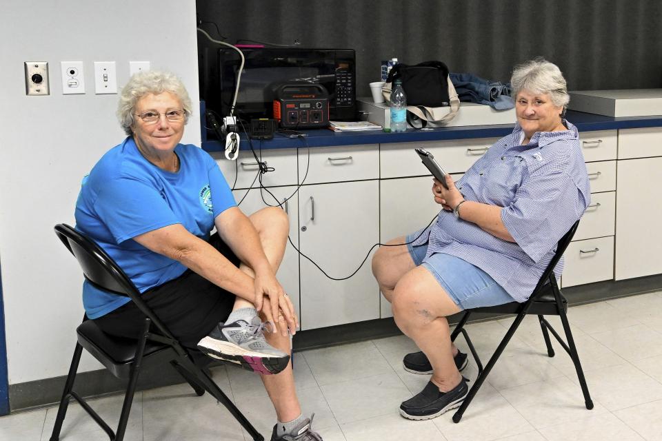 Fran Wilcox, left, and Cynthia Cannon, right, charge their cell phones and battery backup at Bayland Community Center in Houston, Wednesday, July 10, 2024. After Hurricane Beryl slammed into Texas, knocking out power to nearly 3 million homes and businesses. (AP Photo/Maria Lysaker)