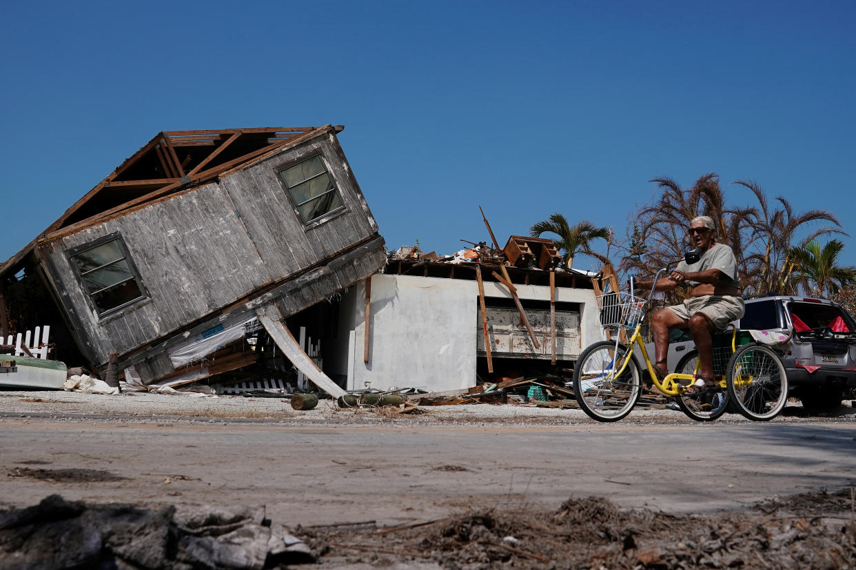 A man rides his trike past a destroyed house following Hurricane Irma in Big Pine Key, Florida, U.S., September 19, 2017. REUTERS/Carlo Allegri