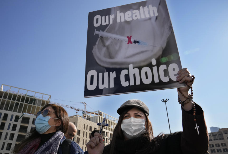 A Protester holds a placard during a rally to protest measures imposed against people who are not vaccinated, in Beirut, Lebanon, Saturday, Jan. 8, 2022. Vaccination is not compulsory in Lebanon but in recent days authorities have become more strict in dealing with people who are not inoculated or don't carry a negative PCR test. (AP Photo/Hussein Malla)