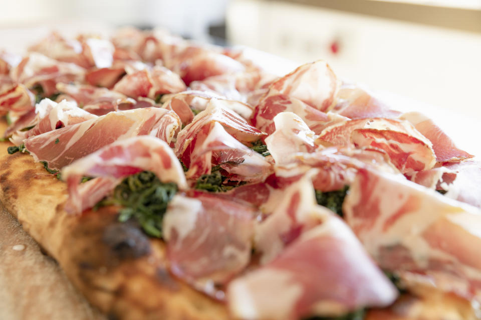 Close-up of a prosciutto and arugula flatbread on a table