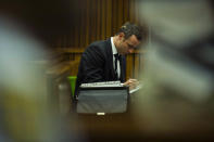 Oscar Pistorius makes notes as he sits in the dock during his trial in court in Pretoria, South Africa, Thursday, March 13, 2014. Pistorius is charged with the shooting death of his girlfriend Reeva Steenkamp, on Valentines Day in 2013. (AP Photo/Alet Pretorius, Pool)