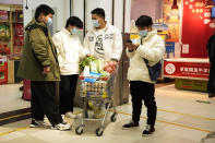 Residents wearing masks wait near a shopping cart of groceries at a supermarket in Beijing, Saturday, Nov. 26, 2022. (AP Photo/Ng Han Guan)