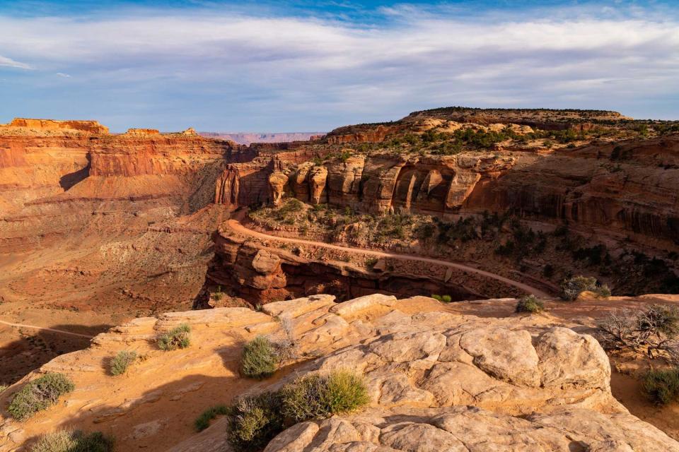 A dirt road curves along cliffs high above a canyon in Canyonlands National park