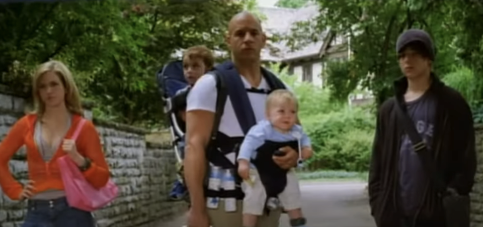 Vin Diesel with child in carrier and co-stars in a scene from "The Pacifier."