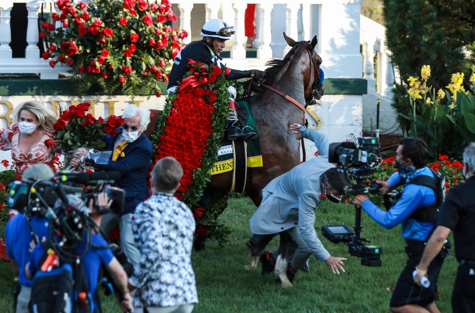 Trainer Bob Baffert, holding some roses, gets knocked down by a jittery Authentic as jockey John Velazquez tries to calm the horse after winning the 2020 Kentucky Derby at Churchill Downs. Sept. 5, 2020