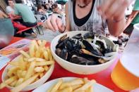 A woman enjoys 'moules-frites' (mussels and French fries) in a restaurant in Lille