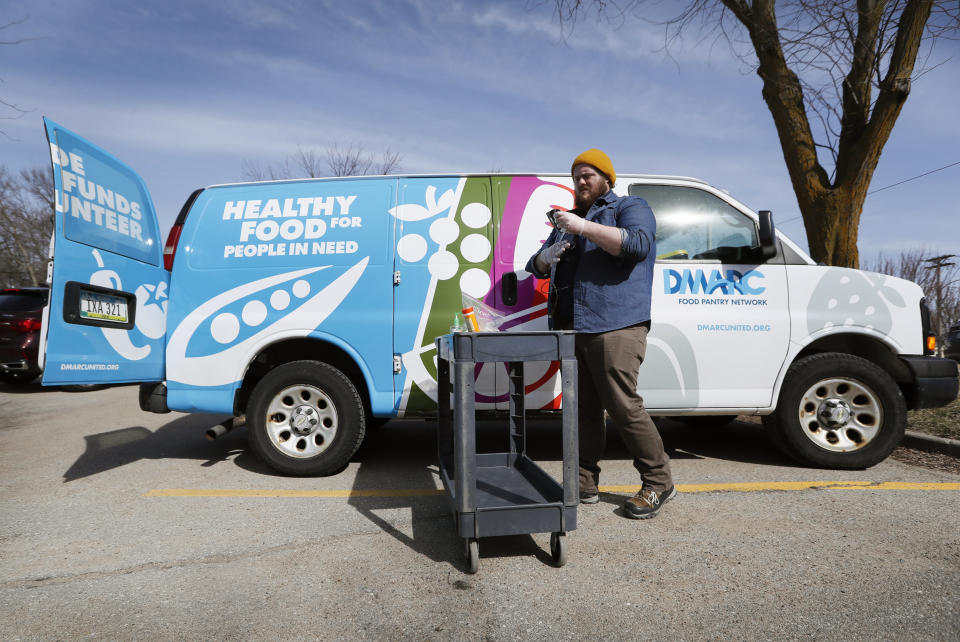 In this Tuesday, March 17, 2020, photo Des Moines Area Religious Council food pantry worker Patrick Minor prepares to pass out food at a senior center in Des Moines, Iowa.  With the new coronavirus leaving many people at least temporarily out of work, food banks and pantries across the U.S. are scrambling to meet an expected surge in demand, even as older volunteers have been told to stay home and calls for social distancing have complicated efforts to package and distribute food. (AP Photo/Charlie Neibergall)