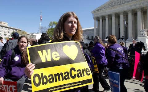 Holding a sign saying "We Love ObamaCare" supporters of health care reform rally in front of the Supreme Court in Washington - Credit: AP Photo/Charles Dharapak