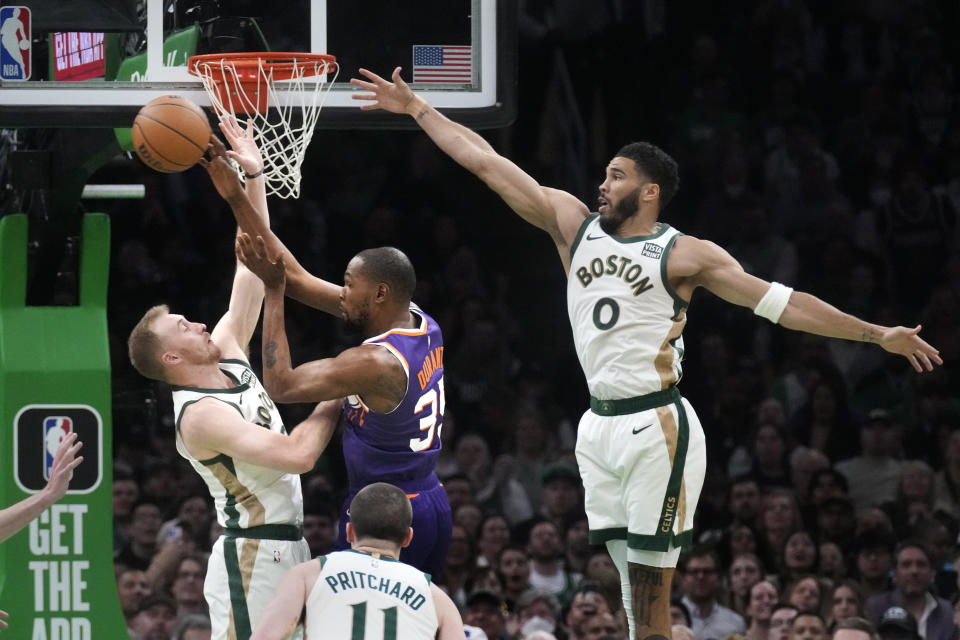 Phoenix Suns forward Kevin Durant (35) passes the ball while covered by Boston Celtics forward Jayson Tatum (0) and Boston Celtics forward Sam Hauser, left, during the first half of an NBA basketball game, Thursday, March 14, 2024, in Boston. (AP Photo/Charles Krupa)