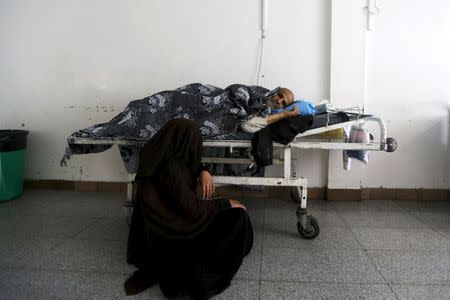 A woman sits near her father as he waits to be given a bed at a government hospital in Sanaa, Yemen, June 24, 2015. REUTERS/Khaled Abdullah