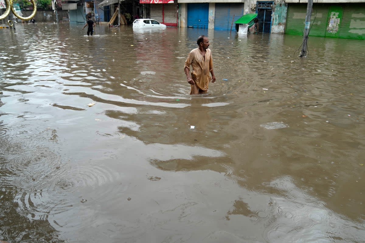 People wade through a flooded area caused by heavy monsoon rainfall in Lahore, Pakistan (AP)