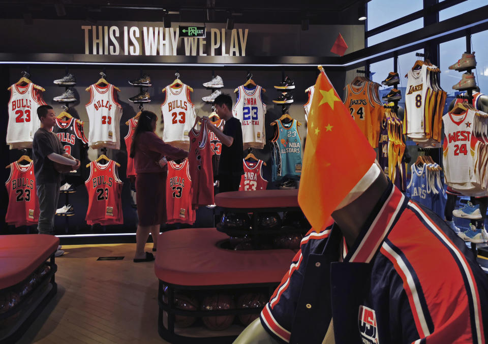 **IMAGE TAKEN WITH MOBILE PHONE CAMERA ** BEIJING, CHINA - OCTOBER 09: A Chinese flag is seen placed on a mannequin wearing the USA basketball uniform  as Chinese shoppers look at clothing in the NBA flagship retail store on October 9, 2019 in Beijing, China. The NBA is trying to salvage its brand in China amid criticism of its handling of a controversial tweet that infuriated the government and has jeopardized the leagues Chinese expansion. The crisis, triggered by a Houston Rockets executives tweet that praised protests in Hong Kong, prompted the Chinese Basketball Association to suspend its partnership with the league. The backlash continued with state-owned television CCTV scrapping its plans to broadcast pre-season games in Shanghai and Shenzhen, and the cancellation of other promotional fan events.  The league issued an apology, though NBA Commissioner Adam Silver angered Chinese officials further when he defended the right of players and team executives to free speech. China represents a lucrative market for the NBA, which stands to lose millions of dollars in revenue and threatens to alienate Chinese fans.  Many have taken to Chinas social media platforms to express their outrage and disappointment that the NBA would question the countrys sovereignty over Hong Kong which has been mired in anti-government protests since June.(Photo by Kevin Frayer/Getty Images)