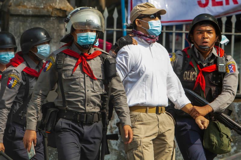 A pro-democracy protester is detained by riot police officers during a rally against the military coup in Yangon