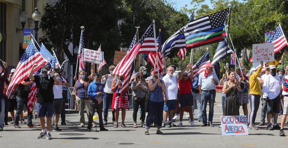 Supporters of District Attorney Dan Dow who want charges filed against activist Tianna Arata wave flags while chanting to disrupt a rally outside the courthouse in San Luis Obispo on Aug. 25, 2020.