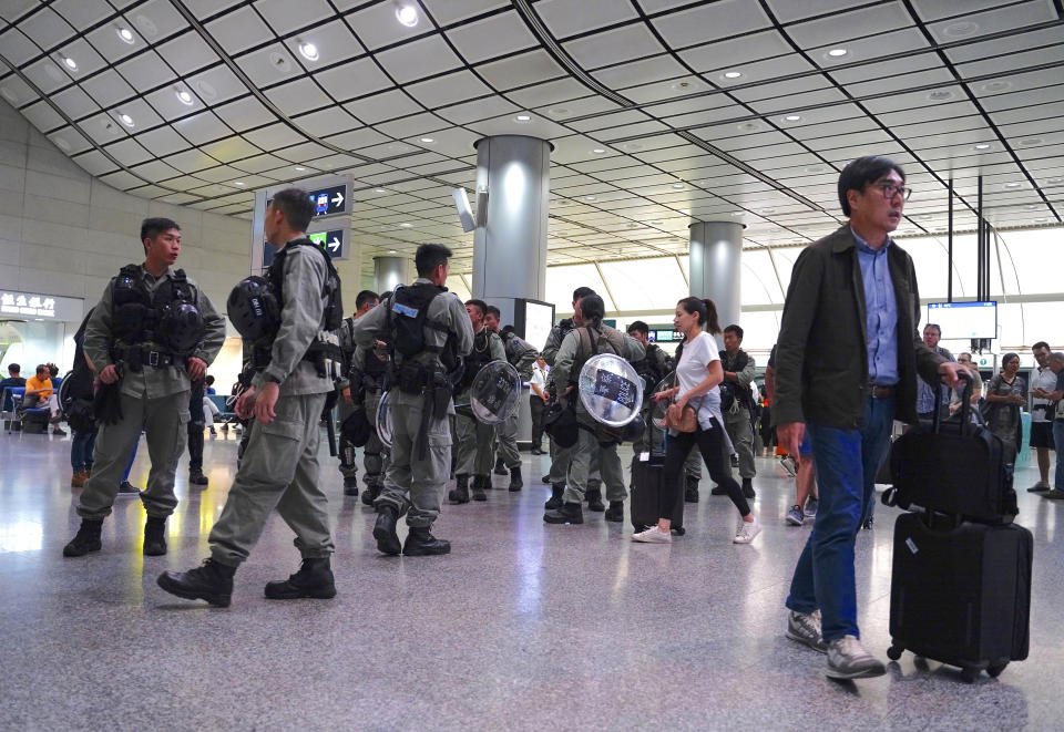 Riot police stand guard at the airport express central station in downtown Hong Kong, Saturday, Sept. 7, 2019. Hong Kong authorities were limiting airport transport services and controlling access to terminals Saturday as they braced for a second weekend of disruption following overnight demonstrations that turned violent. (AP Photo/Vincent Yu)