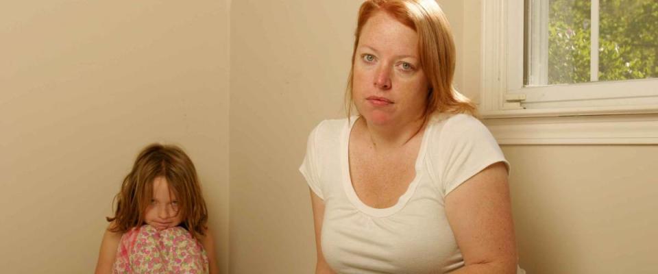 Mother and daughter sitting on a mattress looking sad