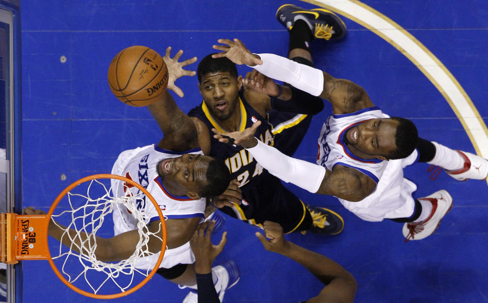 Philadelphia 76ers' Jarvis Varnado, left, and Tony Wroten, right, battle for a rebound against Indiana Pacers' Paul George during the first half of an NBA basketball game on Friday, March 14, 2014, in Philadelphia. (AP Photo/Matt Slocum)