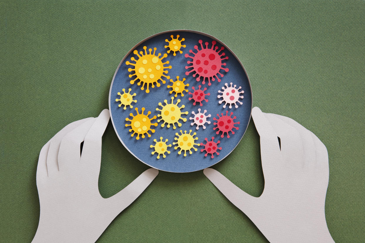 Conceptual paper illustration of human hands and coronavirus in a lab. Flat lay top-down composition on green background.