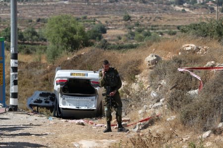 An Israeli soldier stands near the scene of what Israeli military said is a car-ramming attack near the settlement of Elazar in the Israeli-occupied West Bank