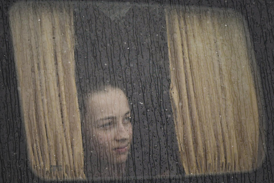 A refugee fleeing the conflict from neighbouring Ukraine sits on a bus, at the Romanian-Ukrainian border, in Siret, Romania, Tuesday, March 8, 2022. (AP Photo/Andreea Alexandru)