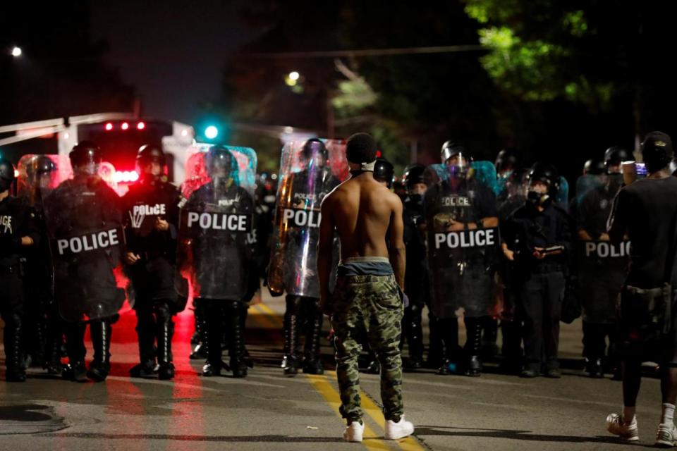 A protester faces off with law enforcement officials during Friday’s protests in St Louis (Reuters)