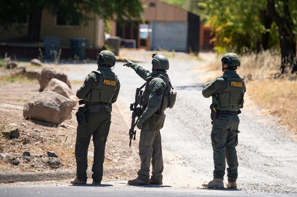 A Placer County Sheriff's deputy, joined by two police officers, points toward a home on Greenbrae Road in Rocklin, Calif., on Sunday, July 9, 2023, after a potential sighting of murder suspect Eric Abril, who escaped earlier in the day from a Roseville hospital.