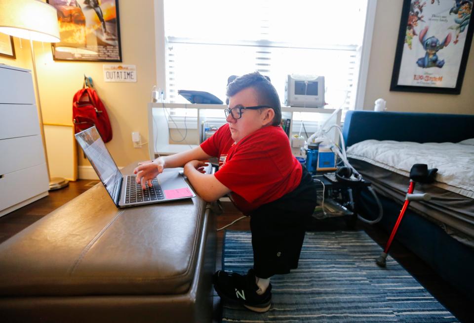 Glendale High School senior Collin Langston works on his laptop in his room on Thursday, May 11, 2023. Langston set a goal his freshman year, to walk at graduation and he is going to accomplish that goal.