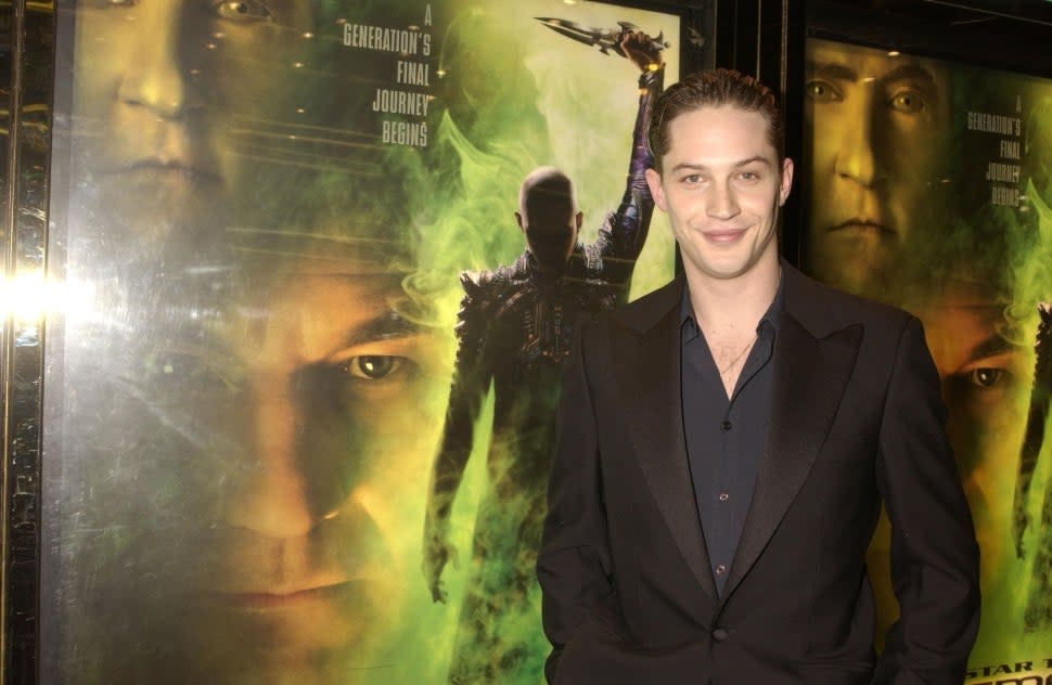 Tom Hardy standing next to a 'Star Trek: Nemesis' poster at the movie's premiere in 2002.