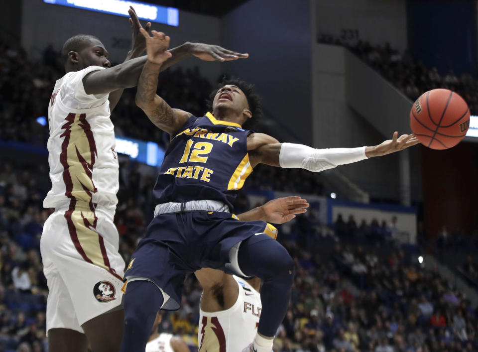 Murray State's Ja Morant (12) passes the ball under defensive pressure from Florida State's Christ Koumadje (21) during the first half of a second round men's college basketball game in the NCAA Tournament, Saturday, March 23, 2019, in Hartford, Conn. (AP Photo/Elise Amendola)