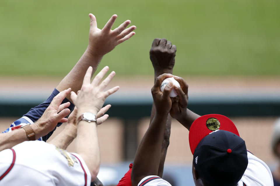 A fan catches a ball thrown into the stands in the sixth inning of a baseball game between the Colorado Rockies and the Atlanta Braves, Sunday, June 18, 2023, in Atlanta. (AP Photo/Butch Dill)