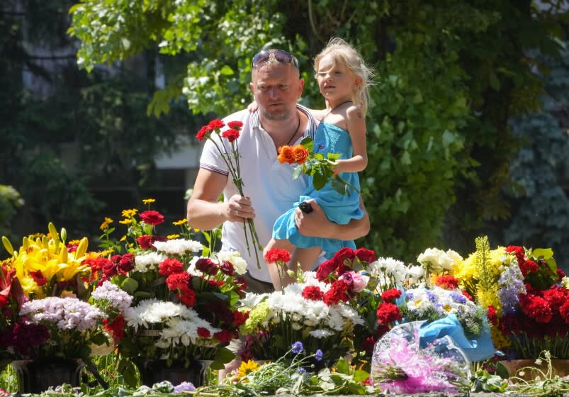 People lay flowers for the victims of the Russian rocket attack at a shopping center in Kremenchuk, Ukraine, Wednesday, June 29, 2022. (AP Photo/Efrem Lukatsky)