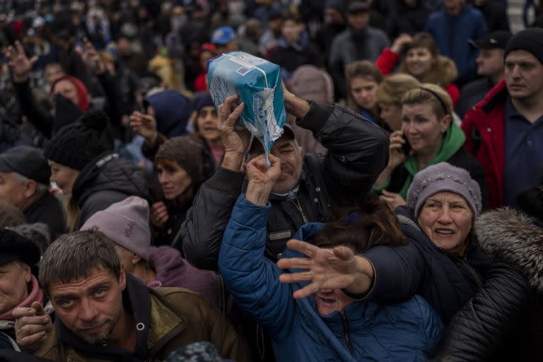 Residentes reunidos en un punto de distribución de ayuda reciben suministros en el centro de Kherson, sur de Ucrania, viernes 18 de noviembre de 2022.