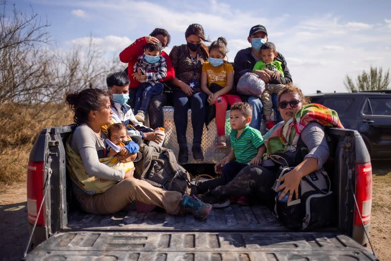 Migrant families sit in back of police truck for transport after crossing the Rio Grande River into thr U.S. from Mexico in Penitas, Texas