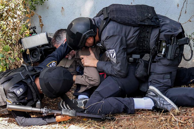 Policías israelíes asisten a un periodista que se cubre durante una alerta de ataque de cohetes de Hamas en la ciudad de Sderot 