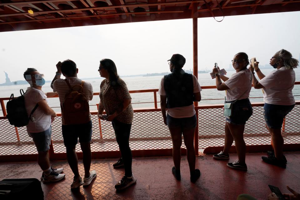 Staten Island ferry commuters take in the view of the Statue of Liberty seen through the haze on July 20, 2021, in New York. Smoke from wildfires across the U.S. West, including Oregon's Bootleg Fire, has wafted over large swaths of the eastern United States. New York City's skies were hazy with smoke from fires thousands of miles away.