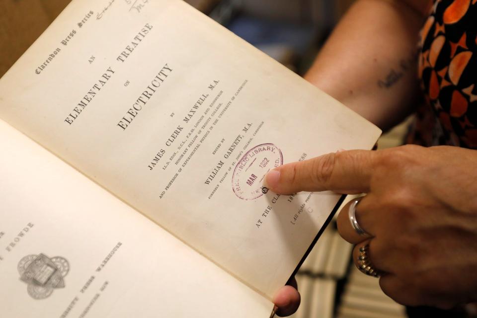 New Bedford Public Library Director, Olivia Melo, points to the stamp dating to 1882 when the New Bedford library system acquired the book. An Elementary Treatise on Electricity by James Clerk Maxwell was returned to the West Virginia University library 100 years after it was taken out of the New Bedford Public library in 1903.