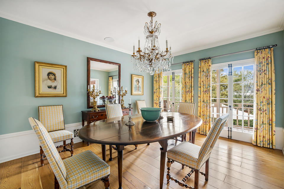 The dining room is enlivened with yellow floral curtains and an antique chandelier.