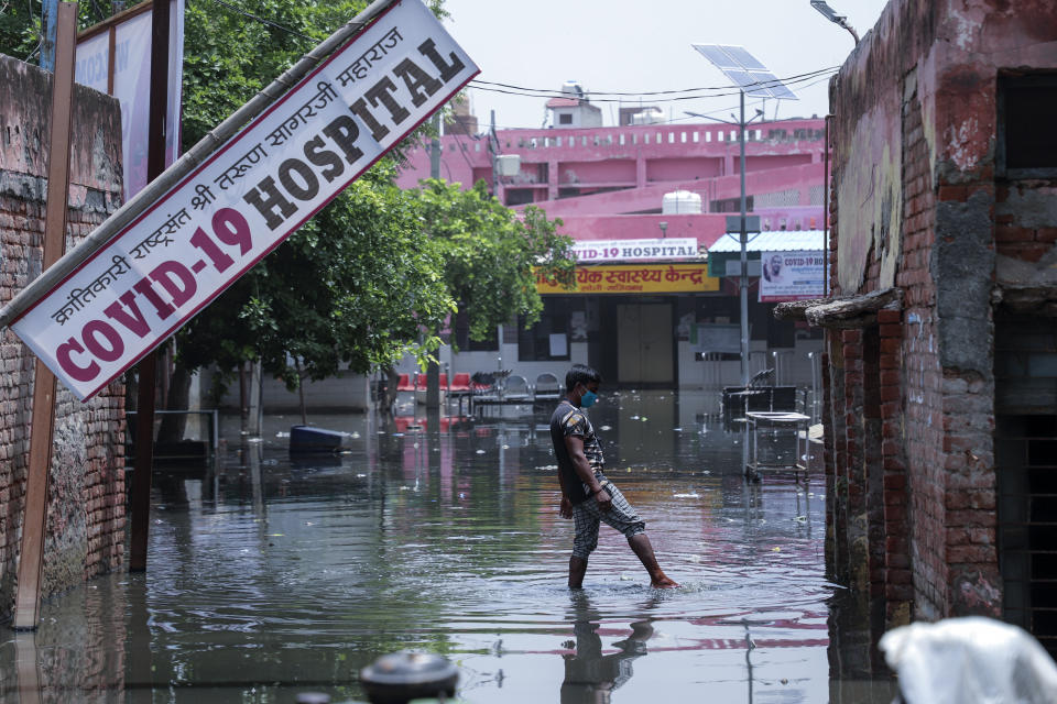 A worker tries to clear water after heavy rains flooded the premises of a COVID-19 hospital being set up at Ghaziabad, outskirts of New Delhi, India, Sunday, May 23, 2021. The hospital is not functional yet. (AP Photo/Amit Sharma)