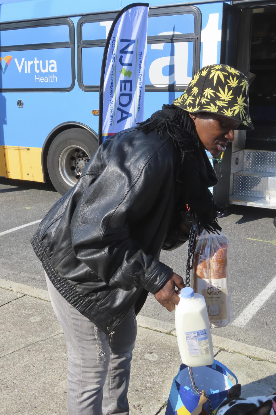 Delorese Butley-Whaley examines her purchases of milk and bread outside a specially modified bus that serves as a mobile supermarket in Atlantic City N.J. on Friday, Dec. 8, 2023. Virtua Health and the New Jersey Economic Development Authority are operating a service to bring fresh groceries and produce to Atlantic City, where plans for what would be the city's first supermarket in nearly 20 years recently fell through. (AP Photo/Wayne Parry)